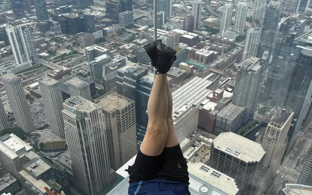 Feet on the glass floor of The Ledge, with streets far below