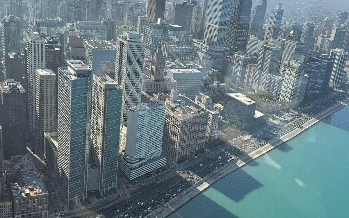 High-rises standing along the lakeside road, turquoise water on the right