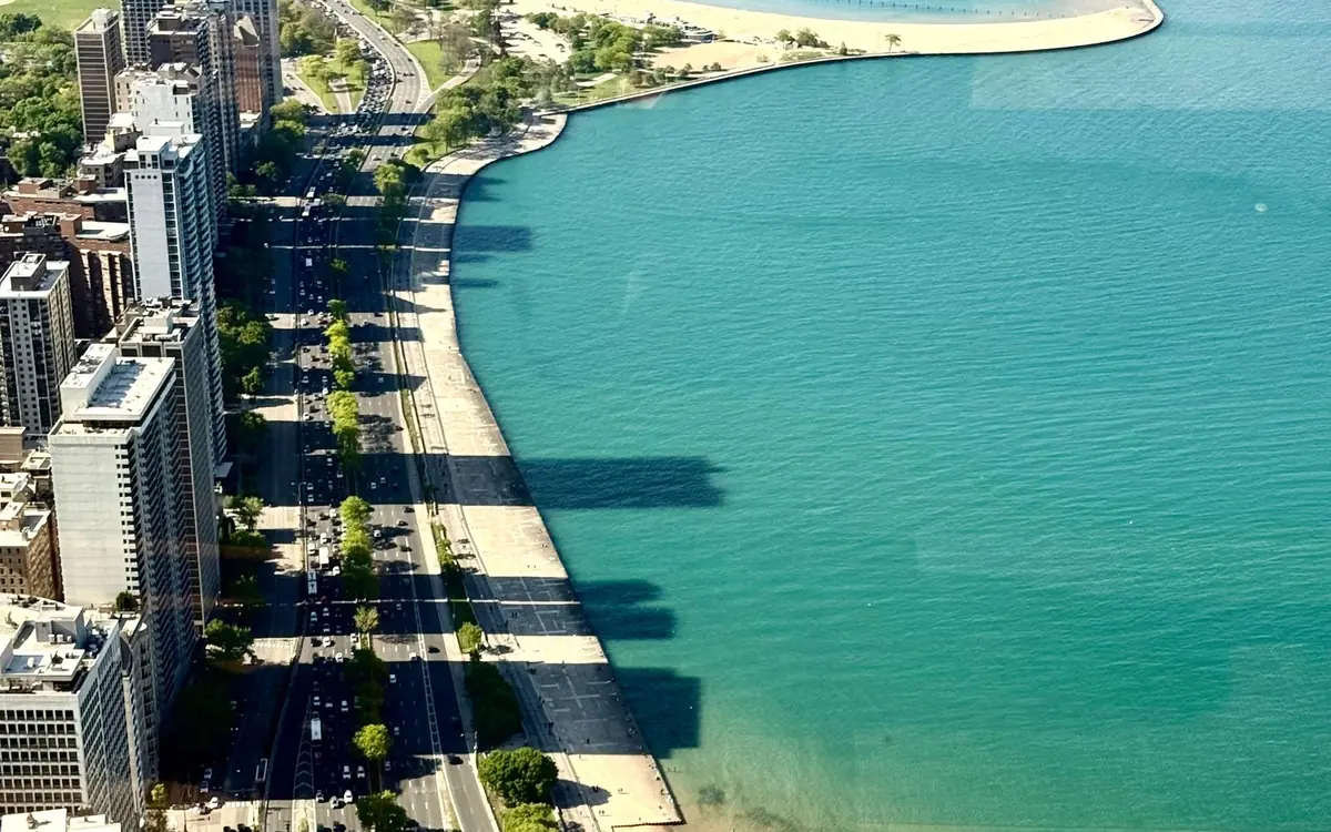 A curved city beach and the lakeshore road, seen from high above