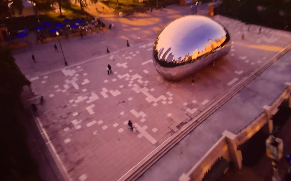 A mirrored sculpture on a stone plaza, seen from above at dusk