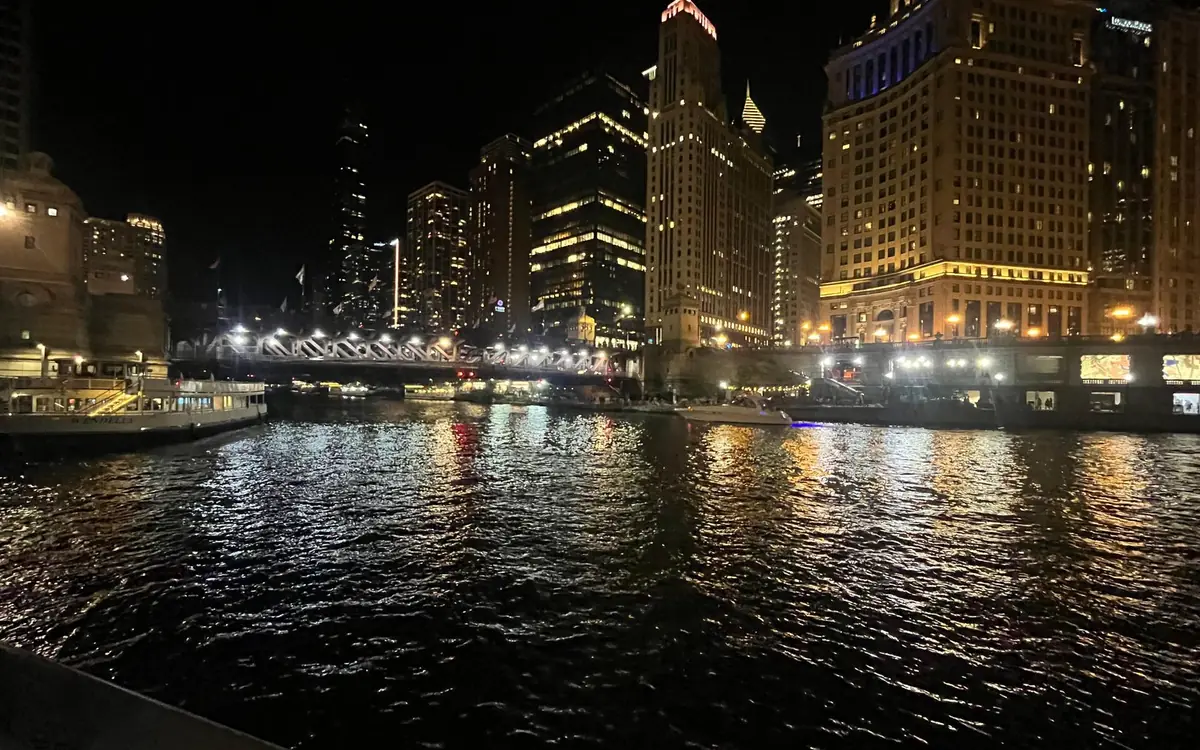Lit towers and a bridge reflected in the river at night
