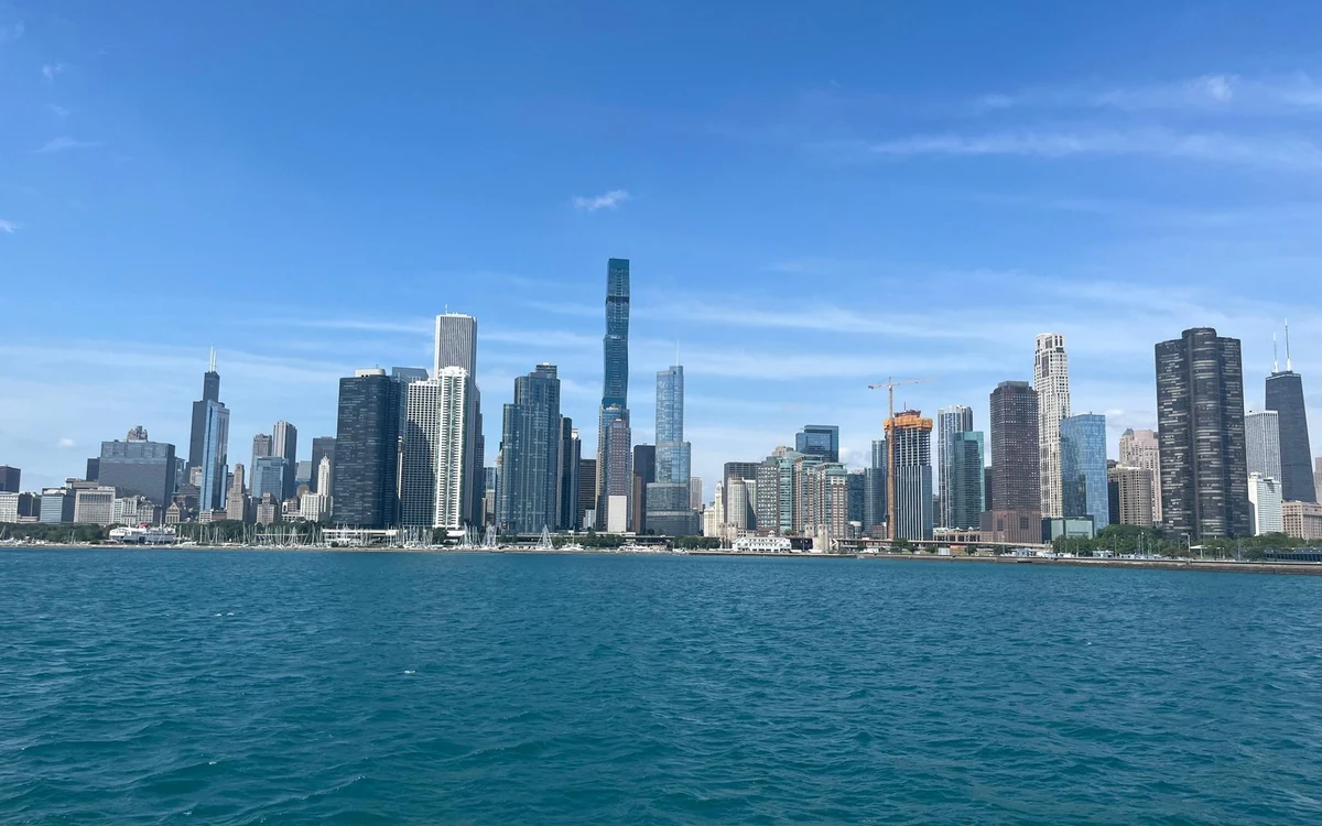 The Chicago skyline seen across blue lake water under a blue sky