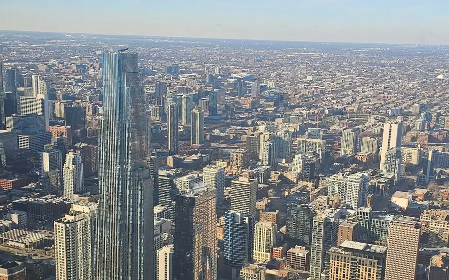 A glass tower and the city grid stretching to the horizon from a high deck