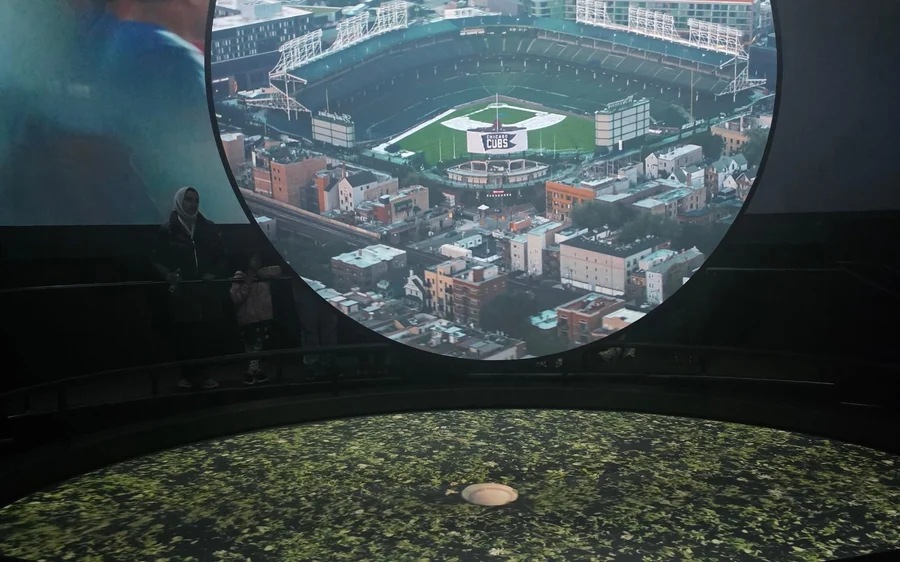A giant domed screen showing a ballpark from the air above the theatre seats